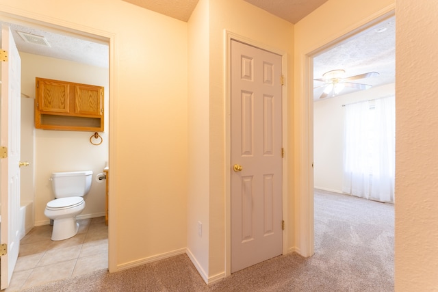 hall with light colored carpet and a textured ceiling