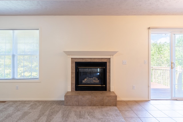 unfurnished living room with a tile fireplace, a textured ceiling, and a wealth of natural light