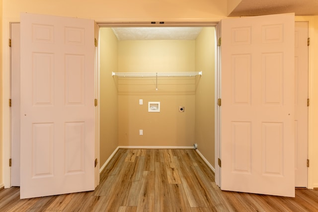 washroom with electric dryer hookup, hookup for a washing machine, light hardwood / wood-style flooring, and a textured ceiling