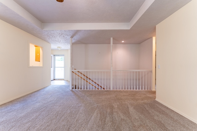 empty room featuring carpet, a textured ceiling, and a tray ceiling