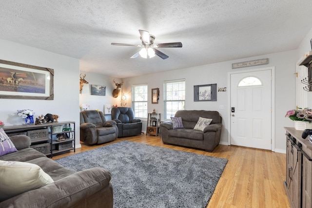 living room with ceiling fan, light hardwood / wood-style floors, and a textured ceiling