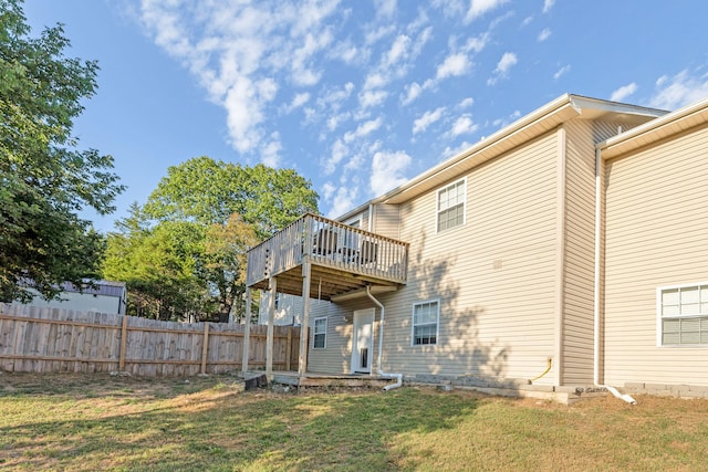 back of property featuring a lawn and a wooden deck