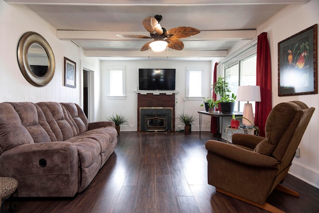 living room with a wood stove, beamed ceiling, dark hardwood / wood-style flooring, and ceiling fan