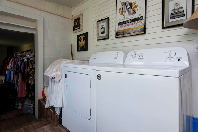 clothes washing area with wood walls, dark hardwood / wood-style floors, and washer and clothes dryer