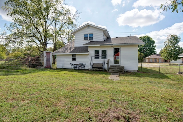 rear view of property featuring a yard and a storage unit