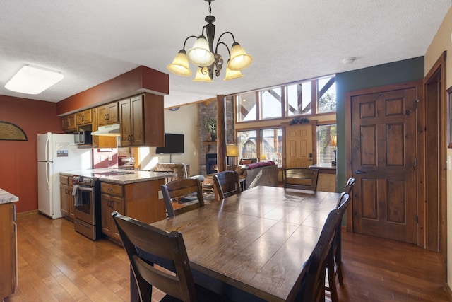 dining area with an inviting chandelier, a textured ceiling, a fireplace, and dark hardwood / wood-style floors