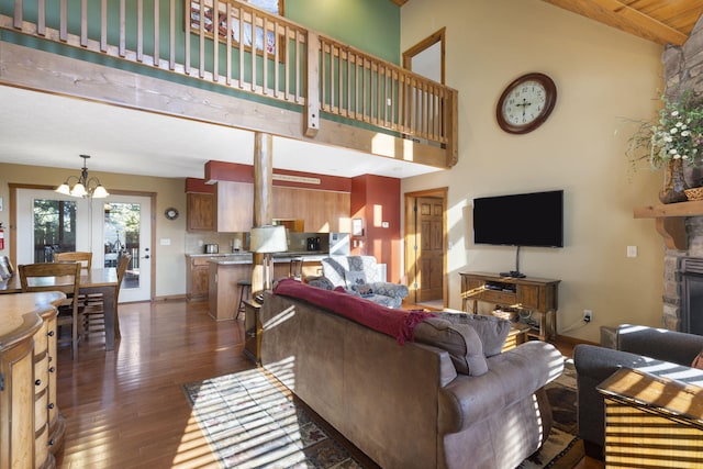 living room with beamed ceiling, a chandelier, dark wood-type flooring, a stone fireplace, and high vaulted ceiling