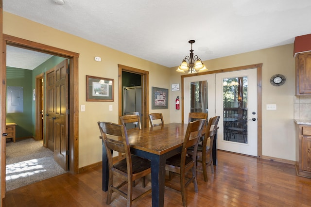 dining area featuring a textured ceiling, a chandelier, and dark hardwood / wood-style flooring