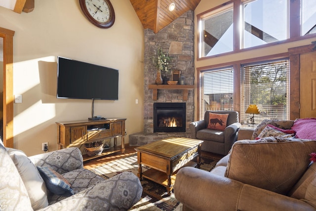 living room featuring high vaulted ceiling, a stone fireplace, and wood-type flooring