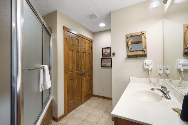 bathroom featuring vanity, combined bath / shower with glass door, a textured ceiling, and tile patterned floors