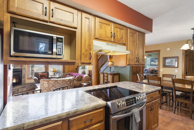 kitchen with stainless steel appliances, dark wood-type flooring, a fireplace, decorative light fixtures, and a textured ceiling