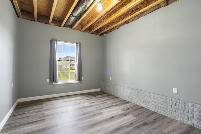 spare room featuring light wood-type flooring and beamed ceiling