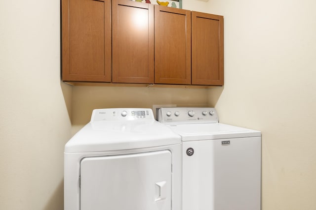 clothes washing area featuring washing machine and dryer and cabinet space