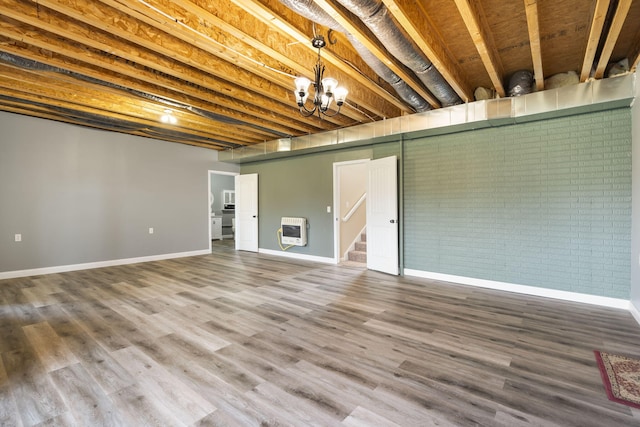 finished basement with wood finished floors, brick wall, baseboards, and heating unit
