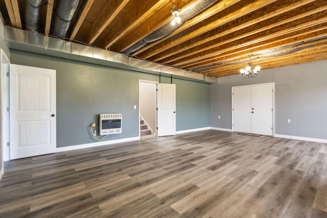 below grade area with stairway, heating unit, wood finished floors, baseboards, and a notable chandelier