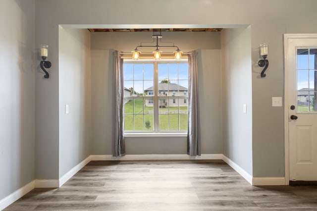 unfurnished dining area featuring light wood-type flooring, a healthy amount of sunlight, and baseboards