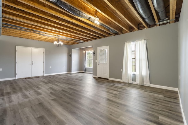 below grade area with dark wood-type flooring, baseboards, and a chandelier
