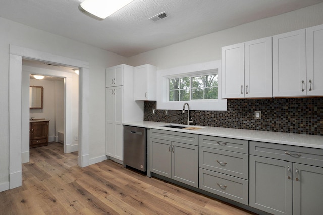 kitchen with sink, stainless steel dishwasher, gray cabinets, light hardwood / wood-style floors, and white cabinets