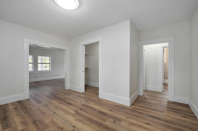 unfurnished bedroom featuring a closet, dark wood-type flooring, and a spacious closet