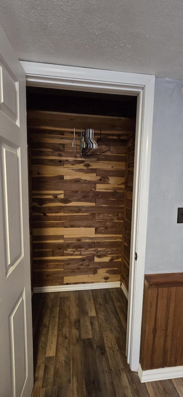detailed view of wood finished floors, wood walls, and a textured ceiling