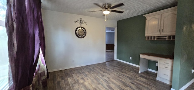 unfurnished dining area with a ceiling fan, dark wood-style floors, and baseboards