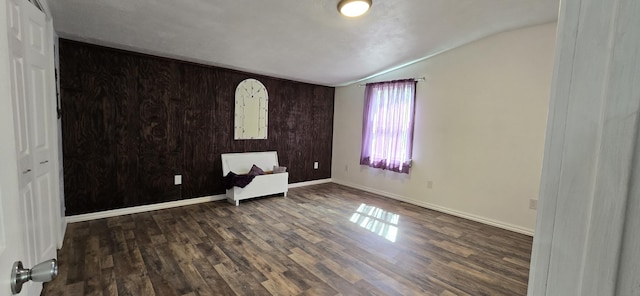 unfurnished room with wood finished floors, lofted ceiling, and baseboards