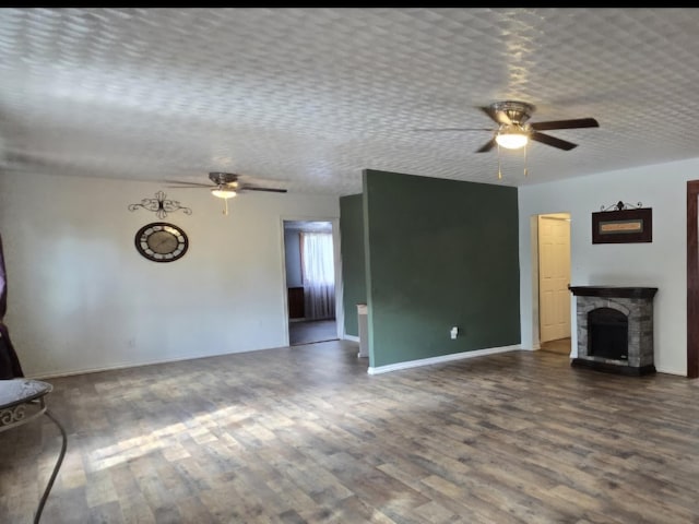 unfurnished living room featuring ceiling fan, wood-type flooring, a fireplace, and a textured ceiling