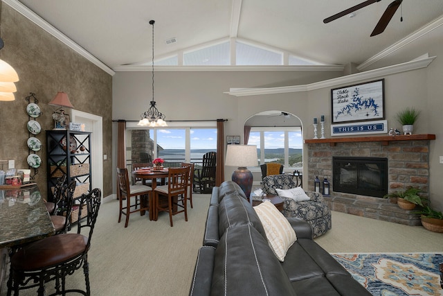 living room featuring carpet floors, ceiling fan with notable chandelier, ornamental molding, and a stone fireplace