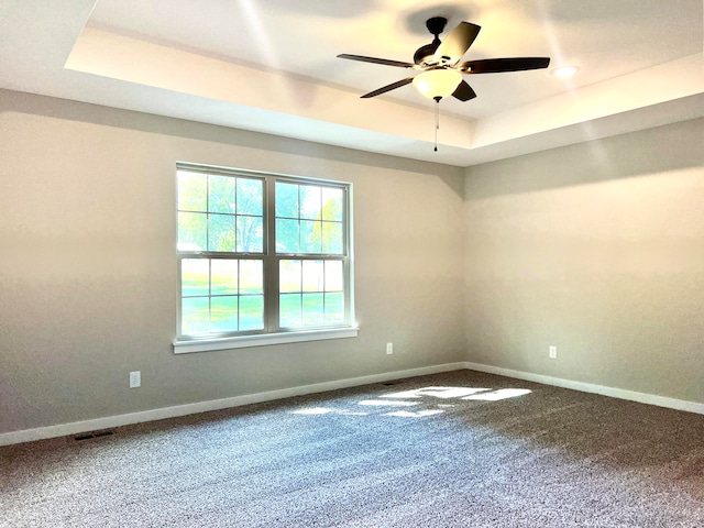 empty room featuring a tray ceiling, carpet, and ceiling fan