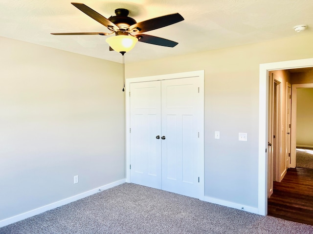 unfurnished bedroom with ceiling fan, a closet, and dark carpet