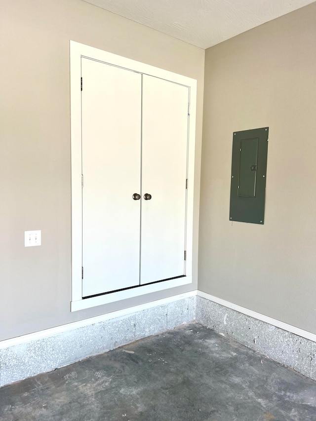 spare room with concrete flooring, electric panel, and a textured ceiling