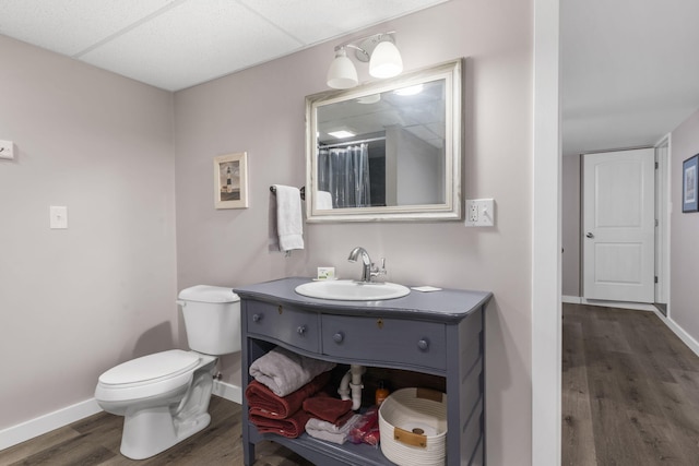 bathroom with toilet, wood finished floors, vanity, and baseboards