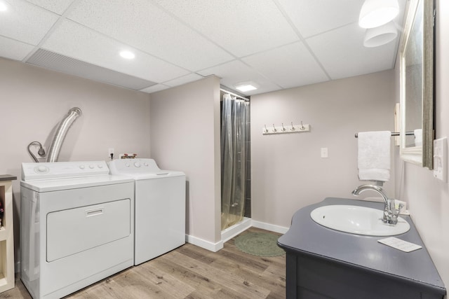 laundry area with light wood finished floors, washing machine and clothes dryer, a sink, laundry area, and baseboards