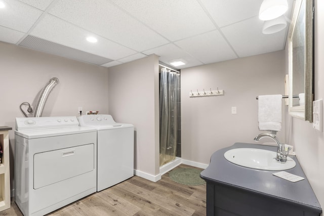 laundry room featuring laundry area, light wood-style floors, baseboards, washer and clothes dryer, and a sink