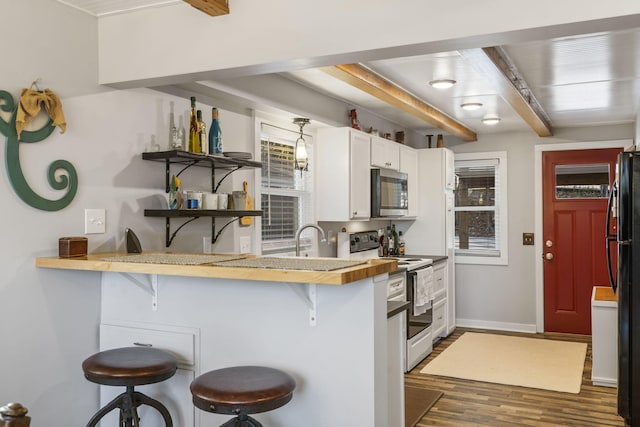 kitchen featuring a breakfast bar area, white electric stove, dark wood-style flooring, stainless steel microwave, and white cabinetry