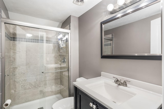 bathroom featuring vanity, toilet, visible vents, and a stall shower