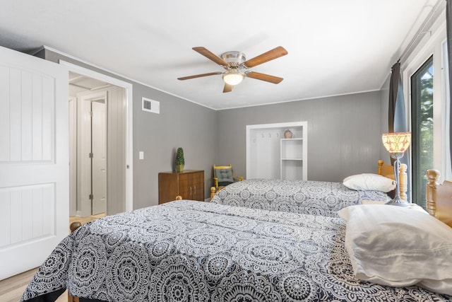 bedroom with visible vents, a ceiling fan, wood finished floors, and ornamental molding