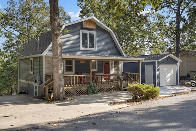 dutch colonial featuring an outbuilding, a porch, an attached garage, a gambrel roof, and roof with shingles