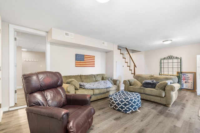 living room with visible vents, stairs, and light wood-style flooring