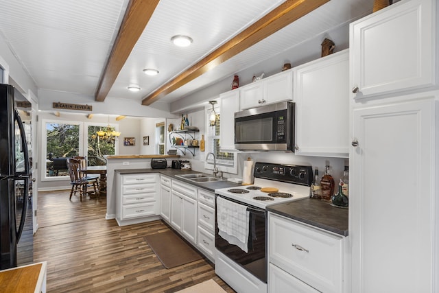 kitchen with dark countertops, stainless steel microwave, freestanding refrigerator, a peninsula, and white range with electric cooktop