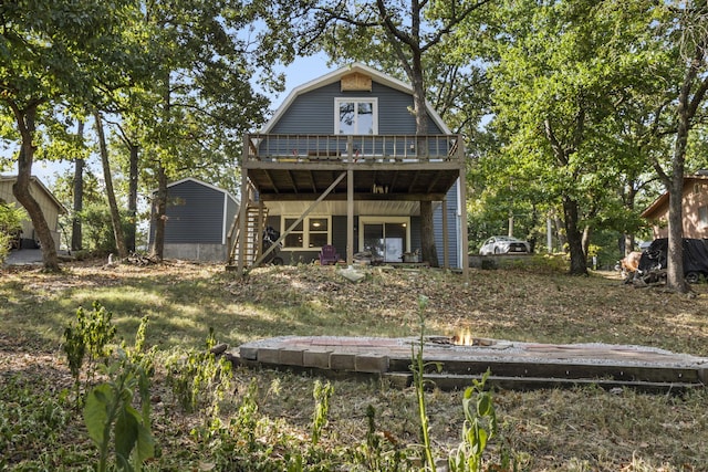 back of house featuring stairs, a deck, and a gambrel roof