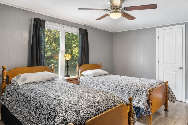 bedroom featuring a ceiling fan, wood finished floors, and ornamental molding