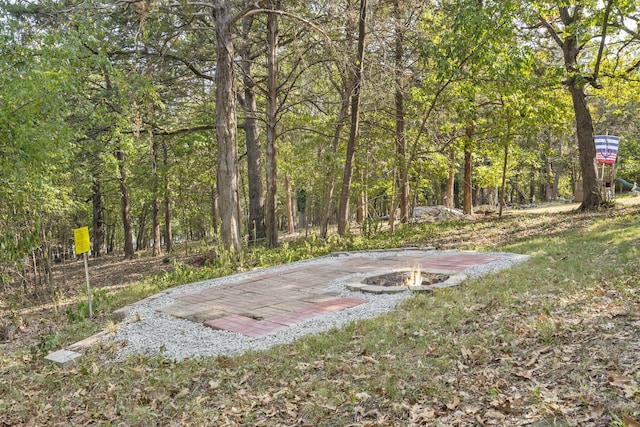 view of yard featuring an outdoor fire pit and a forest view
