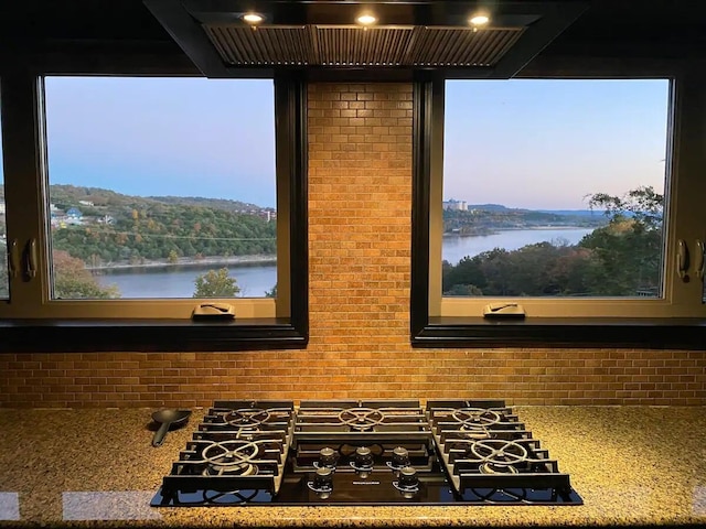 interior space with a water view, light stone counters, and black gas stovetop