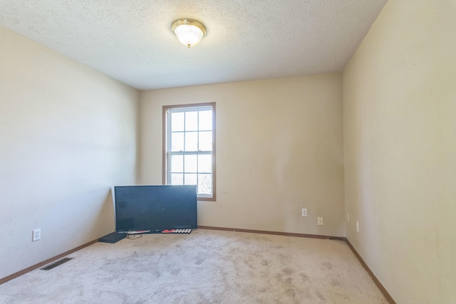 empty room featuring a textured ceiling and light carpet