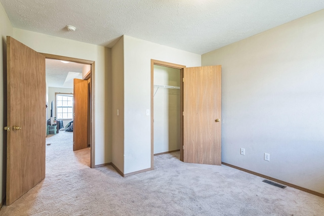 unfurnished bedroom featuring a closet, a textured ceiling, and light carpet