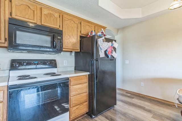 kitchen with black appliances, light hardwood / wood-style flooring, and a textured ceiling