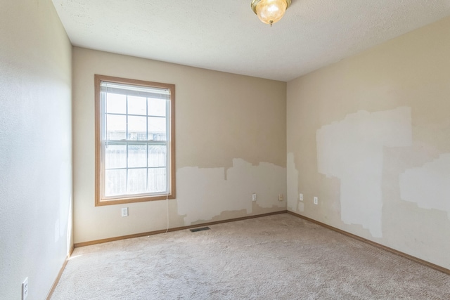 carpeted empty room featuring a textured ceiling