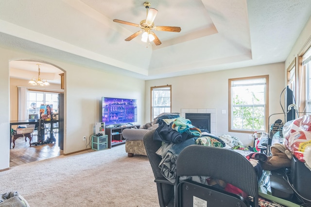 living room featuring ceiling fan with notable chandelier, a fireplace, plenty of natural light, and wood-type flooring