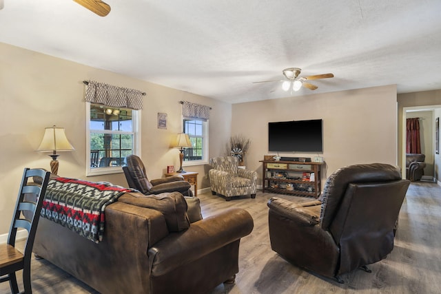 living room featuring ceiling fan, wood-type flooring, and a textured ceiling